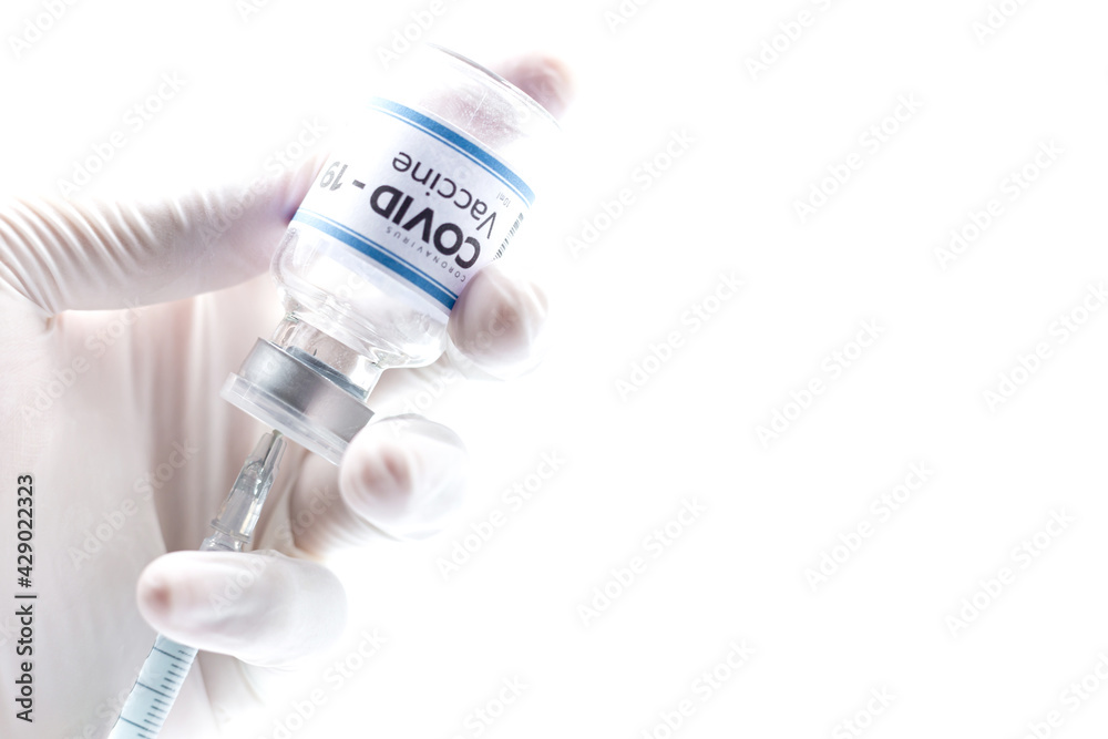 Doctor with surgical glove holding a vaccine vial with the white label written Coronavirus COVID-19 Vaccine, isolated on white background Doctor with surgical glove holding a vaccine vial with the white label written Coronavirus COVID-19 Vaccine, isolated on white background
