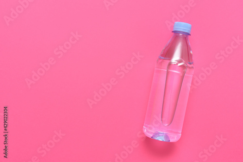 Plastic bottle with water on a pink background with copy space