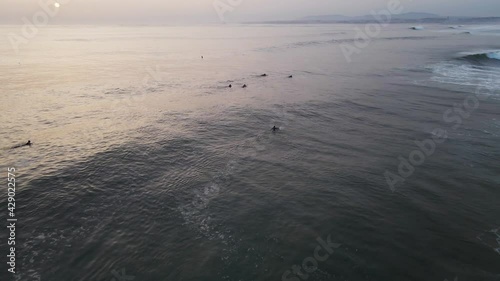 Aerial view of a surfer riding a big waves in Atlantic Ocean open water at sunset along Caparica coastline, Lisbon, Portugal.