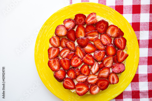 Bright and delicious strawberry cake on a red napkin in a cage