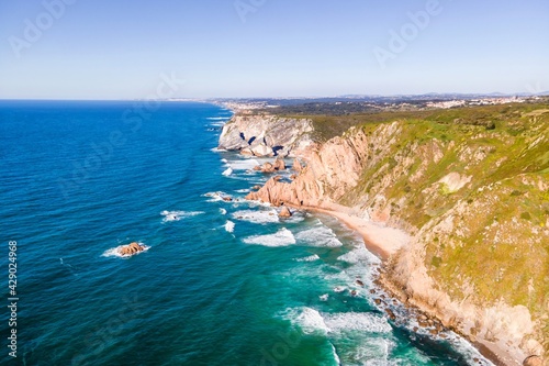 Aerial view of wild coastline with cliffs and rocky promontory near Cabo da Roca facing the Atlantic Ocean, Colares, Lisbon, Portugal.