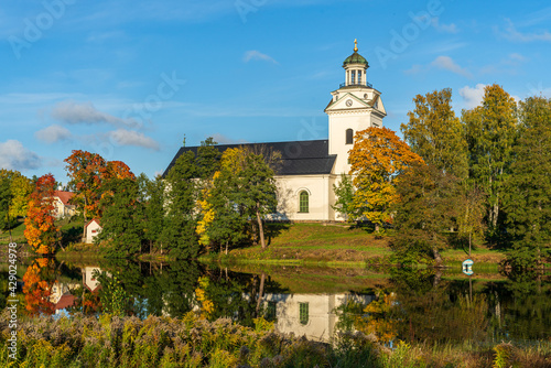 Church by a river in Sweden surrounded by autumn colored trees