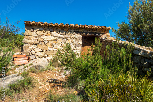 Exterior of a stone-built mountain hut on a sunny day.