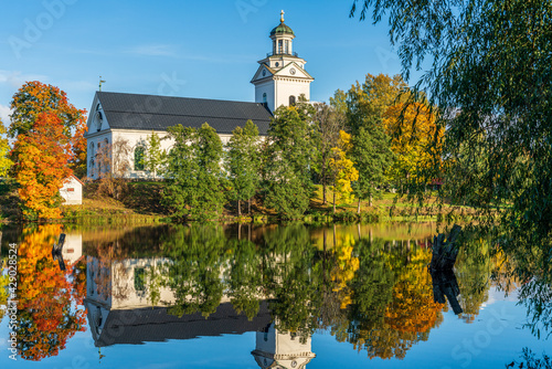White church by a river in Sweden surrounded by autumn colored trees