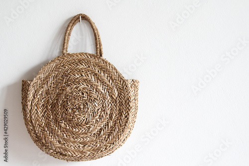 The straw bag hanging on white concrete wall.