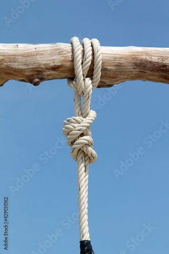 White rope tied on wooden twigs and blue sky background.