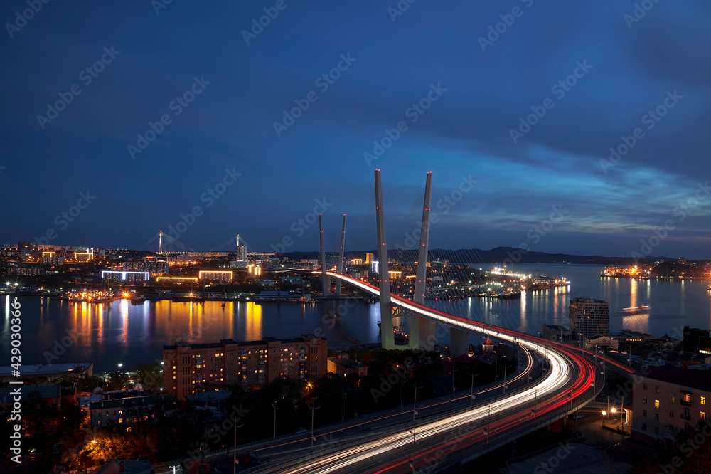 View of the night Vladivostok, the Golden Horn Bridge across the Golden Horn Bay, the Russian Bridge and city blocks. Far East, Russia View of the night Vladivostok, the Golden Horn Bridge across the Golden Horn Bay, the Russian Bridge and city blocks. Far East, Russia