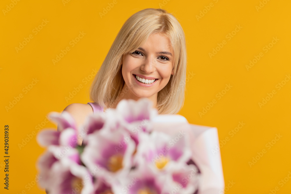 Portrait of happy young lady with spring bouquet of tulips, receiving flowers as special gift, yellow background Portrait of happy young lady with spring bouquet of tulips, receiving flowers as special gift, yellow background