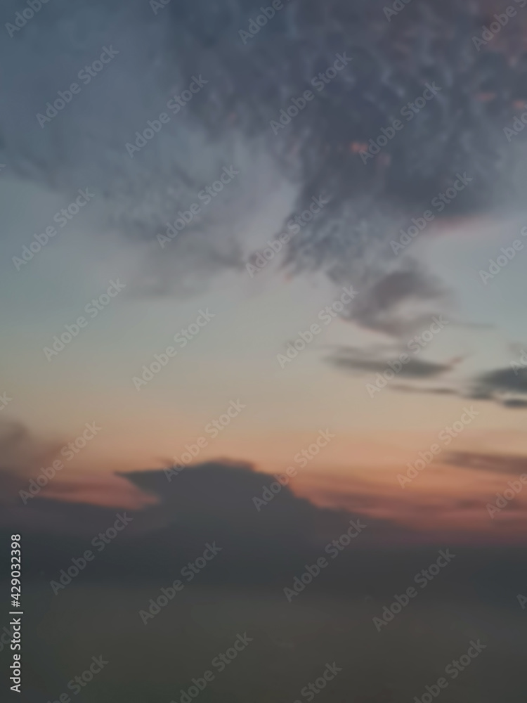 Abstract blurred of the Dark morning sky, soft red sky, among the grey and blue clouds, use as a nature background, defocused style. Vertical image.