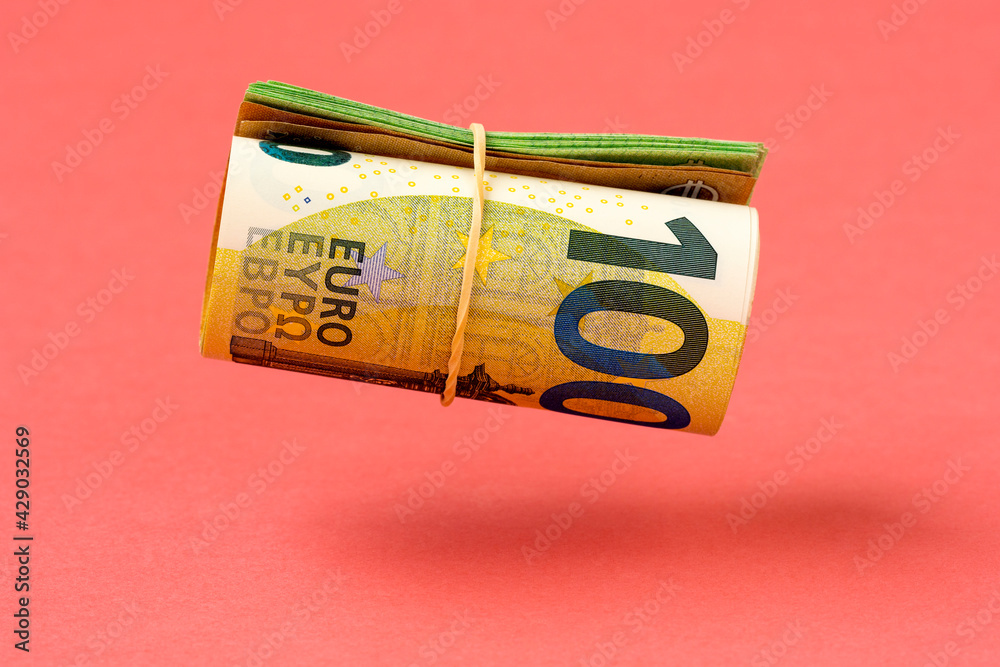 Roll of euro currency levitating over pink background - obrazy, fototapety, plakaty 