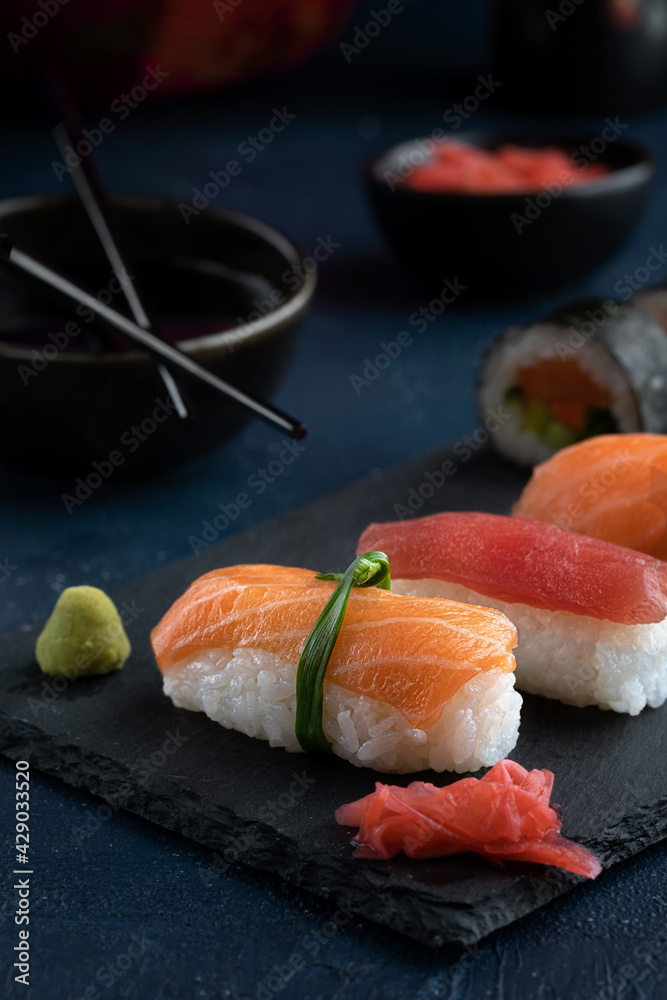 Rainbow Sushi Roll and nigiri with salmon, tuna, avocado and vegetables placed on black rock.Japan restaurant menu.Japanese food. Rainbow Sushi Roll and nigiri with salmon, tuna, avocado and vegetables placed on black rock.Japan restaurant menu.Japanese food.