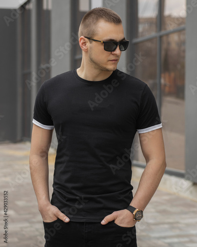 Stylish muscular men wearing black t-shirt posing on the street