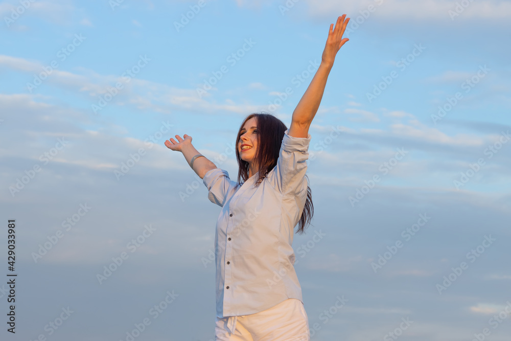Happy woman with open arms. European woman on clouds blue sky background. Wellbeing and freedom concept. Happy woman with open arms. European woman on clouds blue sky background. Wellbeing and freedom concept.