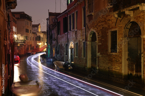 Venice, light trails of a boat on a small canal in Castello, Italy