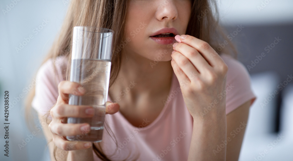 Unrecognizable young lady holding glass of water, taking pill at home, panorama Unrecognizable young lady holding glass of water, taking pill at home, panorama