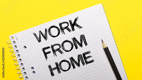 White notebook with inscription WORK FROM HOME written in black pencil on a bright yellow background.