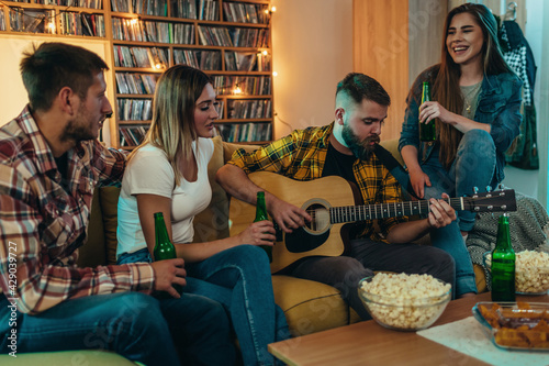 A group of friends playing guitar and drinking beer at home