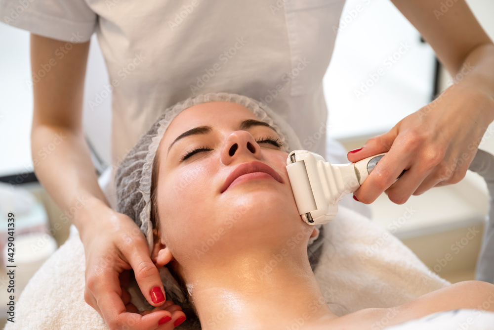 Closeup of young smiling woman enjoying lifting and rejuvenating procedure in beauty salon. Closeup of young smiling woman enjoying lifting and rejuvenating procedure in beauty salon.