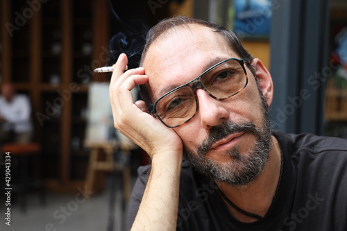 Canvas Print Closeup portrait of tired matured man sitting in aa bar with cigarette in his hand
