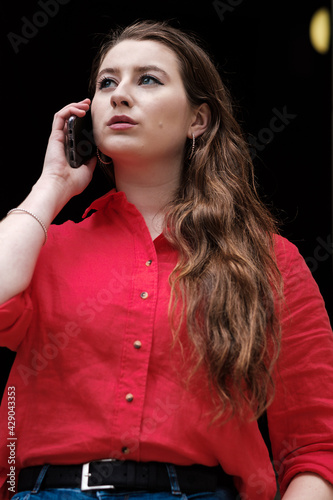 Portrait of a young woman  in red shirt using her smartphone.