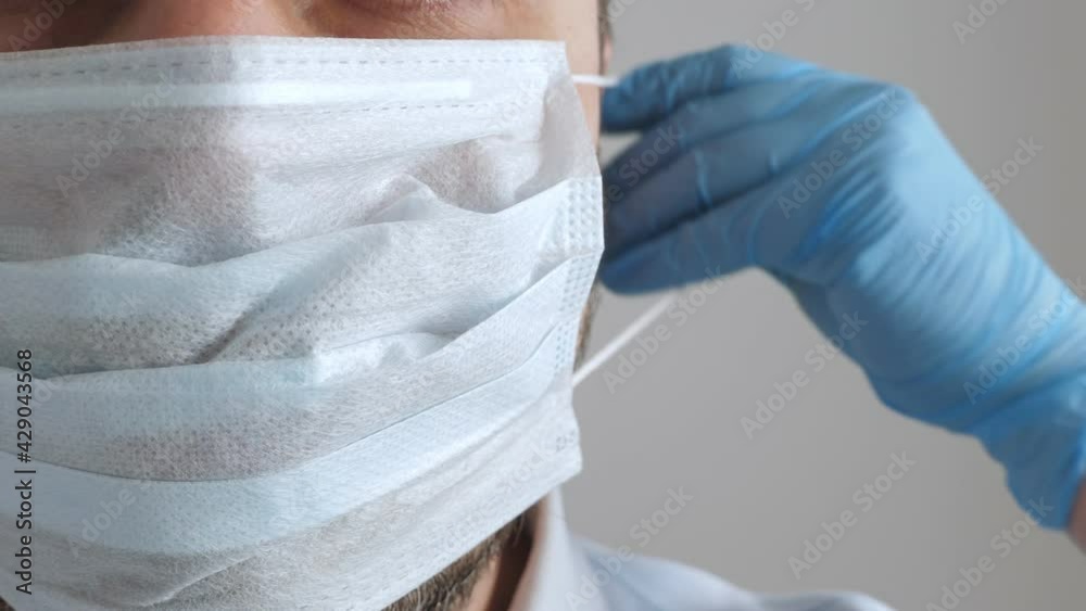 Man in medical protective mask and blue latex gloves. Macro face shot