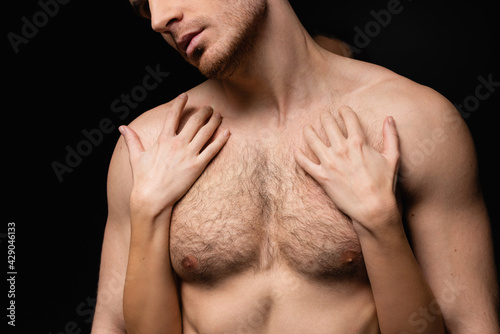 cropped view of woman hugging shirtless and muscular man isolated on black.