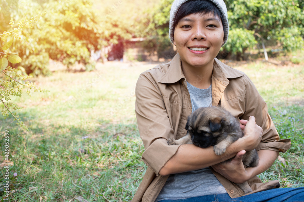 Happy Asian owner carrying, hugging Carrying adorable puppies dog her sitting green grass Happy Asian owner carrying, hugging Carrying adorable puppies dog her sitting green grass