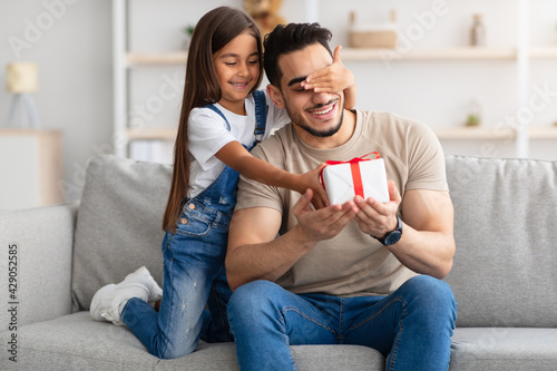 Little girl celebrating father's day, greeting excited dad with box