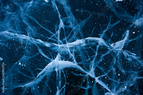 Frozen Baikal lake with cracks and methane bubbles on the transparent ice surface. Winter abstract and blue ice background.