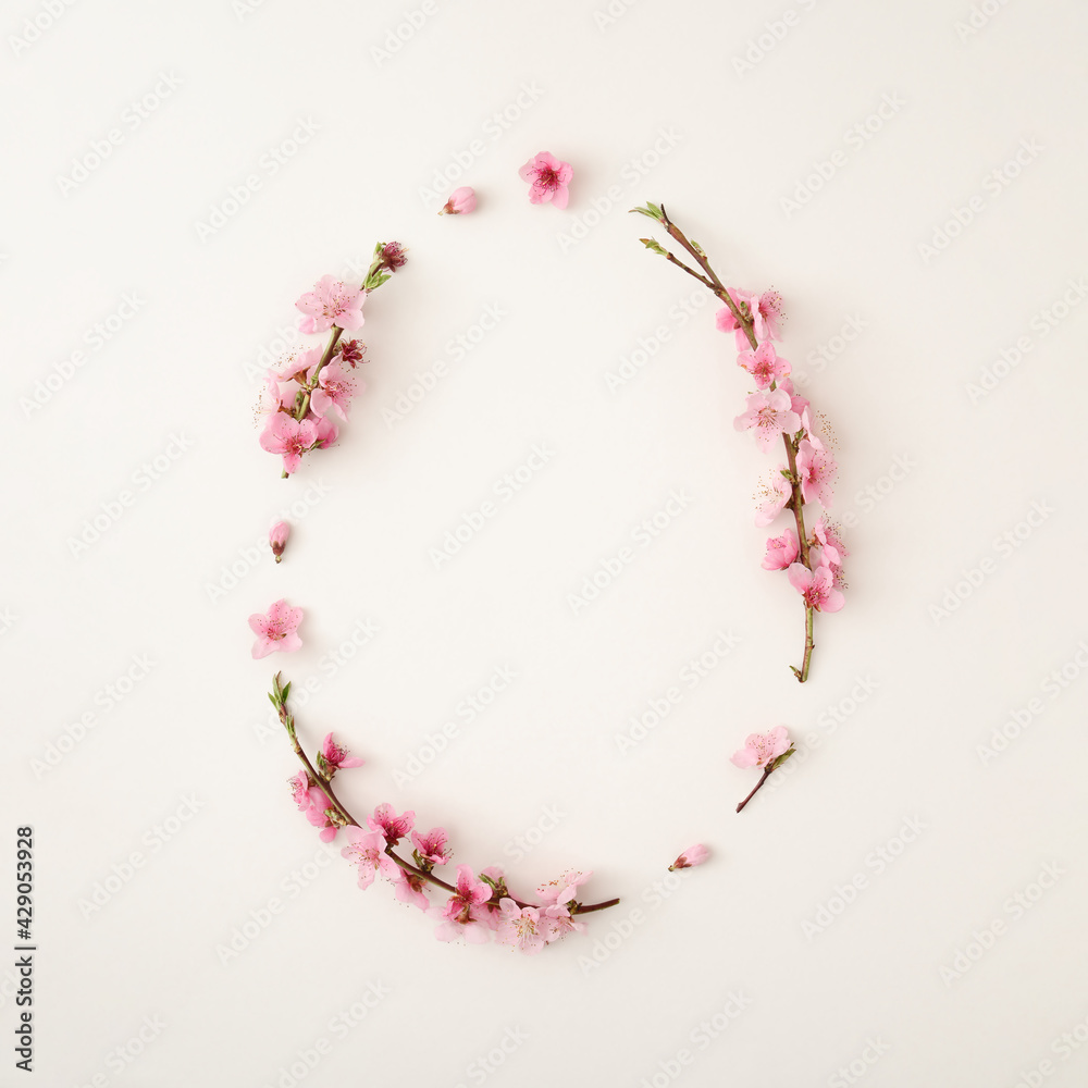 Easter egg shape copy space made of cherry blossom flowers and green leaves. Spring creative background concept. Minimal flat lay nature.