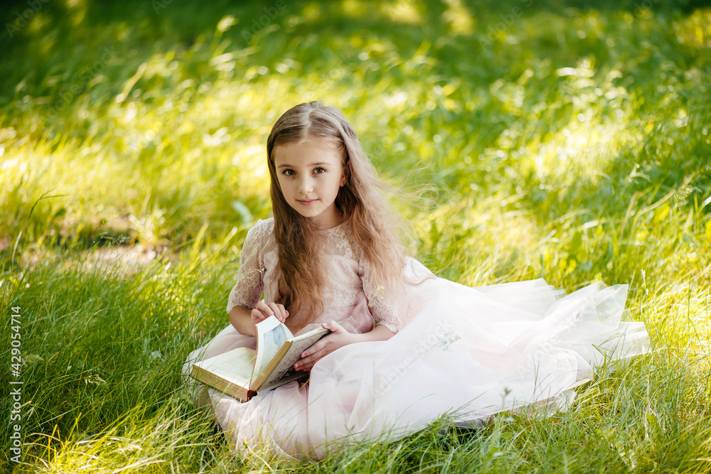 Adorable girl in summer park reading book Adorable girl in summer park reading book