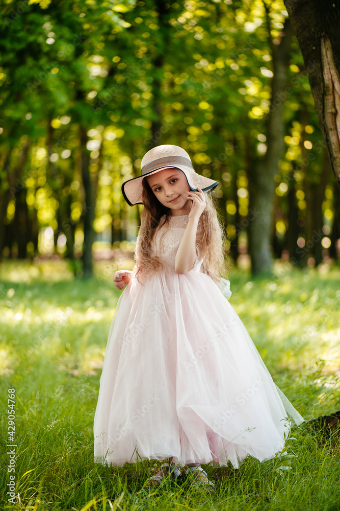 Little girl in a dress and hat in the park