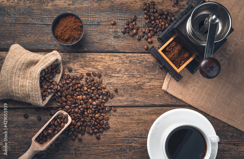 Retro coffee background with copy space. A cup of coffee, coffee beans and a coffee grinder on a wooden background.