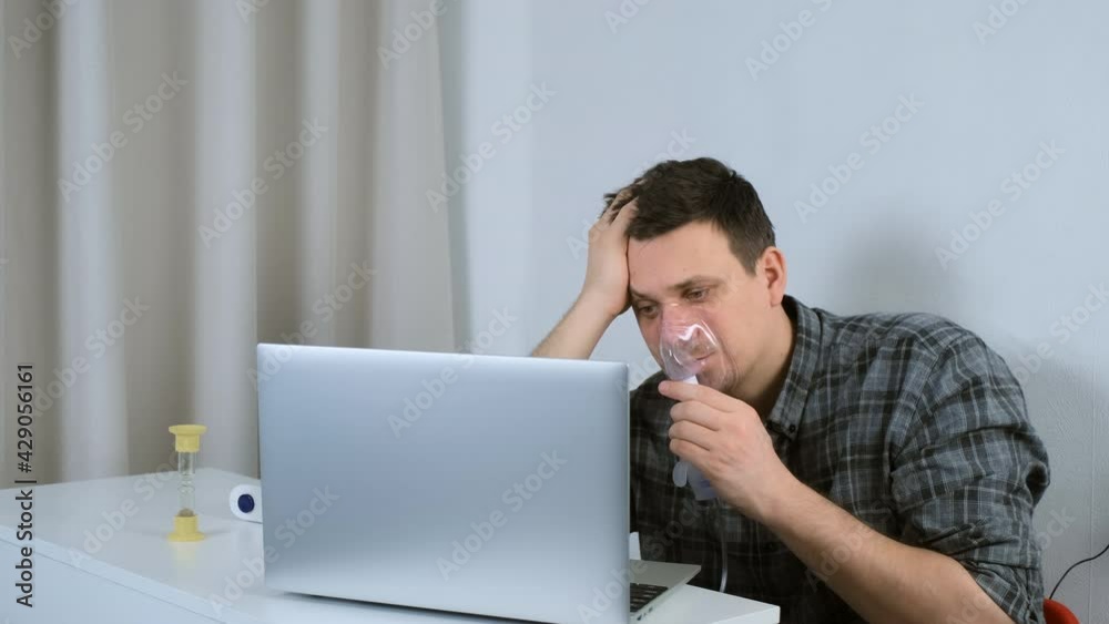 Portrait of sick sleepy man is using nebulizer and inhaler for treatment at home and working on laptop. He breathing in mask. Fibrosis, covid-19, asthma copd. Treatment, cure and procedure, therapy. Portrait of sick sleepy man is using nebulizer and inhaler for treatment at home and working on laptop. He breathing in mask. Fibrosis, covid-19, asthma copd. Treatment, cure and procedure, therapy.