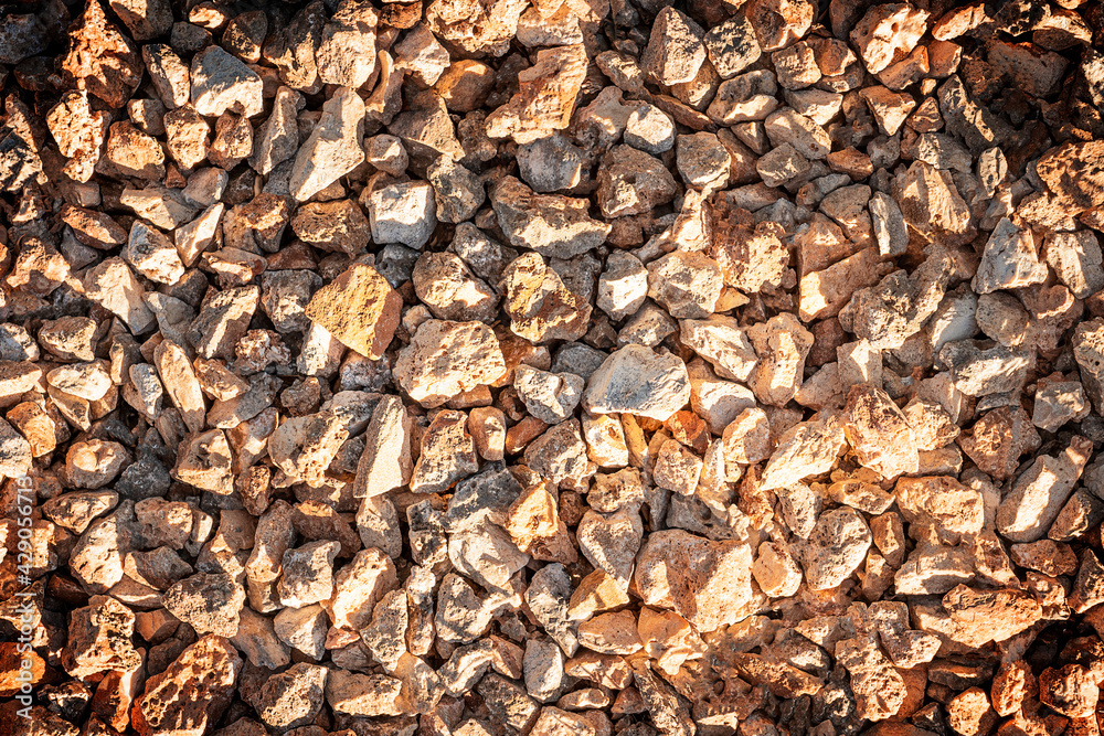 Background or backdrop made of small pieces of brown pebbles or break stones at a bright sunny day lit with warm sunlight. Vacation or travelling concept. Horizontal orientation image Background or backdrop made of small pieces of brown pebbles or break stones at a bright sunny day lit with warm sunlight. Vacation or travelling concept. Horizontal orientation image