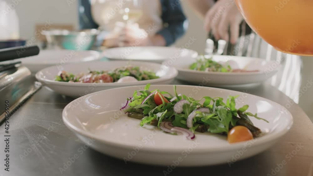 Slowmo close up of unrecognizable male hands decorating just cooked dishes on white plates with fresh red onion slices Slowmo close up of unrecognizable male hands decorating just cooked dishes on white plates with fresh red onion slices
