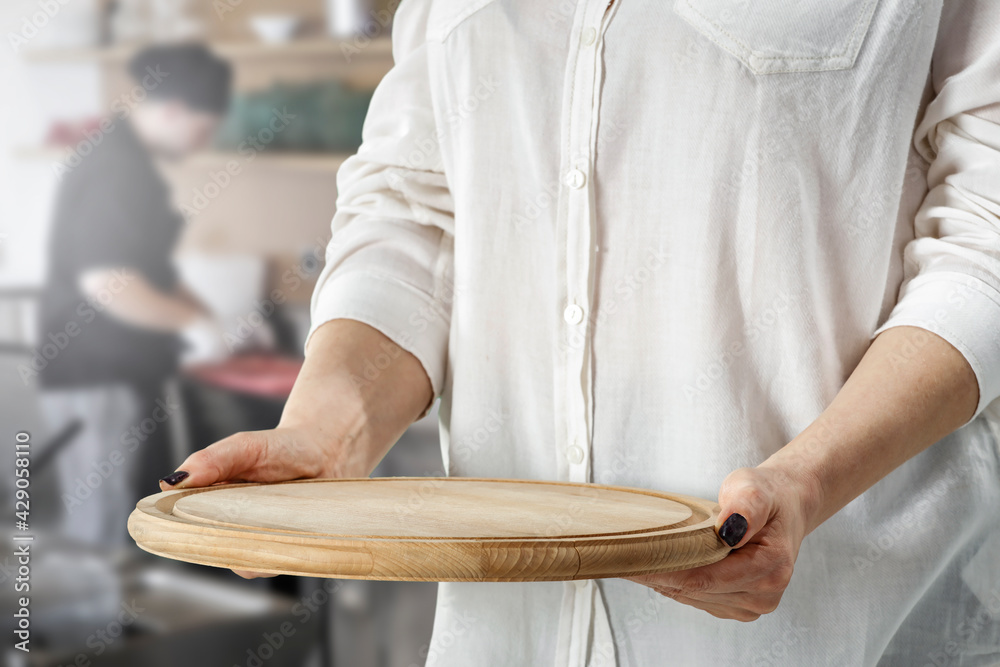 A wooden tray in a woman's hand against the backdrop of a nice place A wooden tray in a woman's hand against the backdrop of a nice place