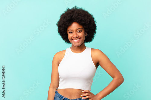 afro black woman smiling happily with a hand on hip and confident, positive, proud and friendly attitude
