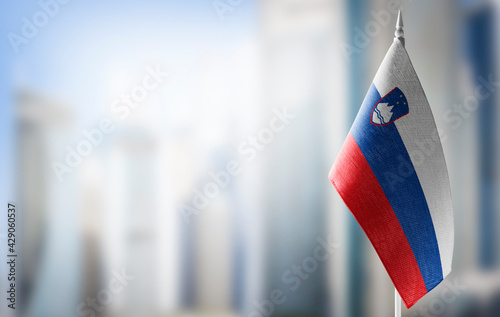 A small flag of Slovenia on the background of a blurred background photo