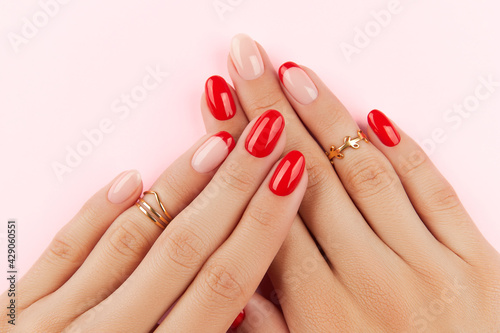 Womans hands with red modern manicure over pink background. Manicure design trends