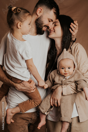 Portrait of a young family with two children in his arms photographed on a monochrome background