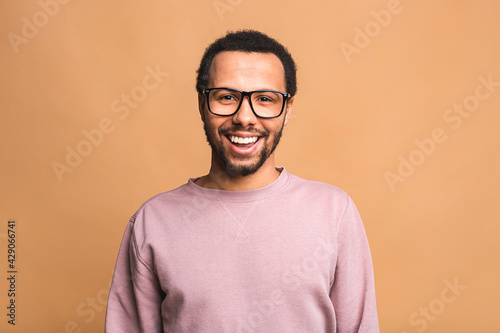 A young happy smiling funny black African American male isolated against beige background. © denis_vermenko