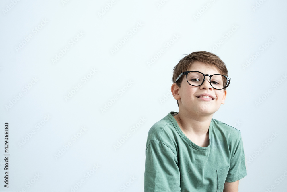 Surprised boy in a green T-shirt and glasses pensive scratches his head. Copy space.