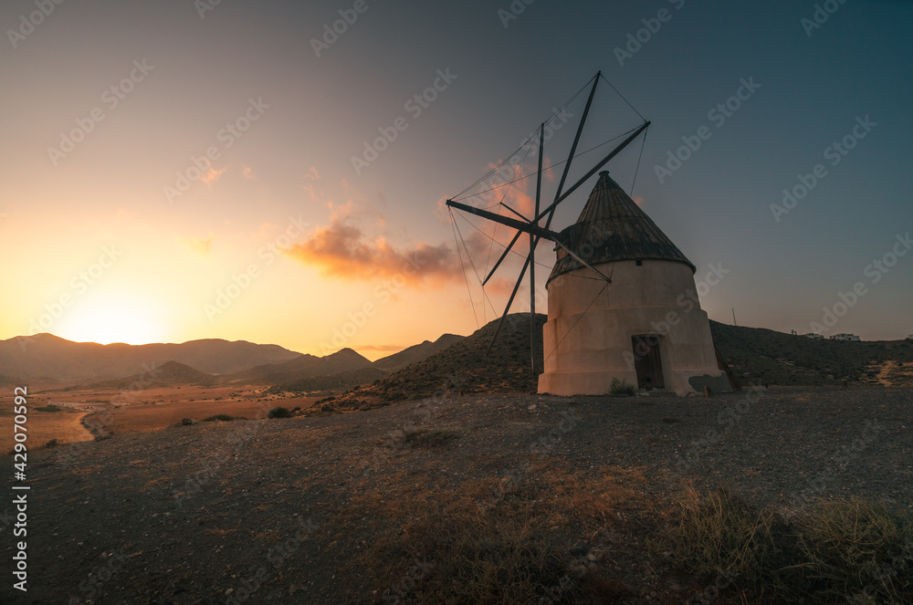 Impressive windmill on the beach of Los Genoveses at sunset, situated near the village of San Jose in Almeria, Andalucia, Spain. Old windmill, renewable energies and ecology.