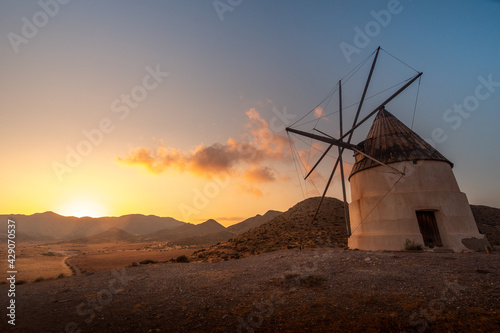 Impressive windmill on the beach of Los Genoveses at sunset, situated near the village of San Jose in Almeria, Andalucia, Spain. Old windmill, renewable energies and ecology.