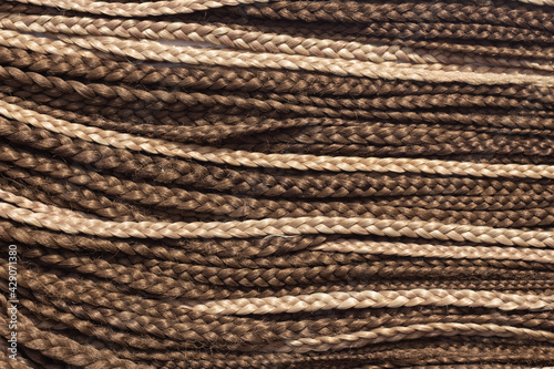 Texture of thin brown African braids, hair close-up braided in pigtails dreadlocks, Afro style
