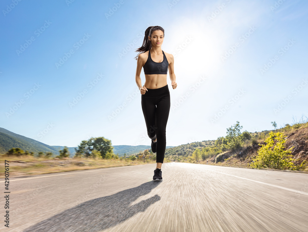 Young slim female jogging outdoors on an open road