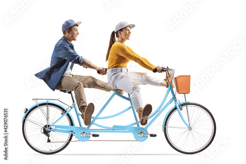 Full length profile shot of a young male and female riding a tandem bicycle and lifitng legs photo