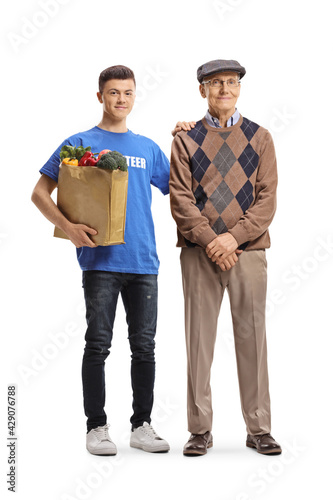 Young male volunteer helping an elderly man with grocery shopping