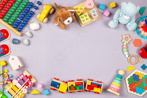 Baby kids toys frame. Colorful educational wooden plastic and fluffy toys for children on gray background. Top view, flat lay